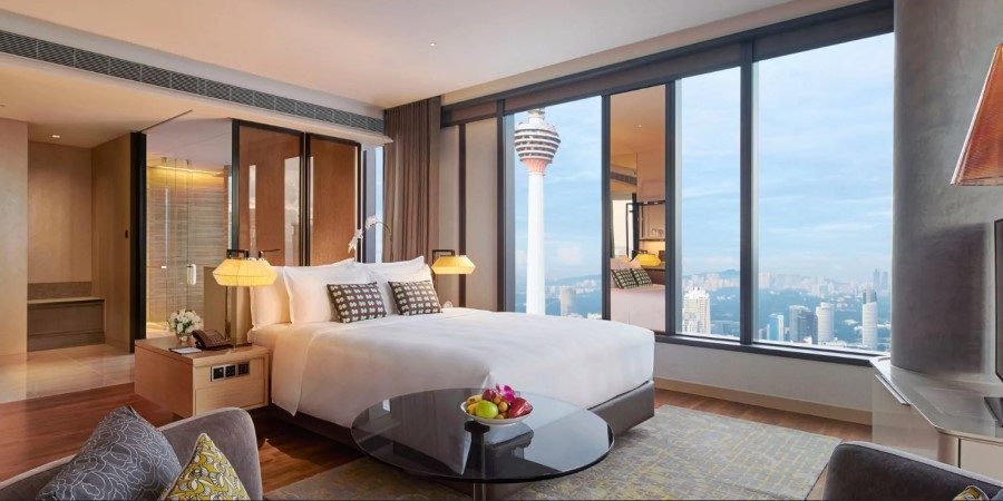 A hotel room featuring a large window with a panoramic view of the city skyline.